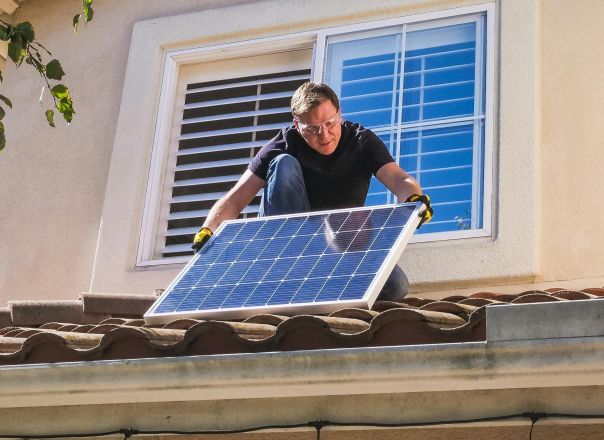 Solar technician installing photovoltaic panels on a sunny rooftop.